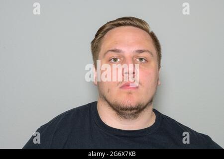 Serious young blond man with goatee beard in his twenties staring intently at the camera in a frontal head and shoulders portrait on white Stock Photo