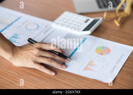 Close up of analysts team working on their financial report with calculator and laptop on wooden table. Stock Photo