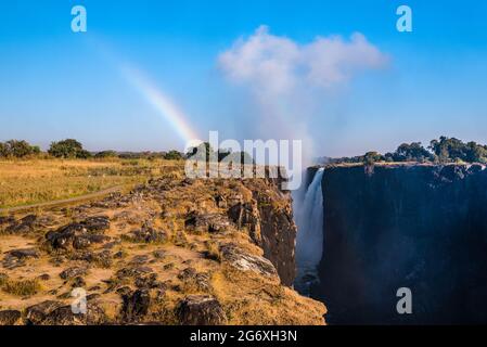 View of the main descent at Victora Falls from the the Danger Point, the easternmost part of the park on the Zimbabwean side, with the rainbow created Stock Photo