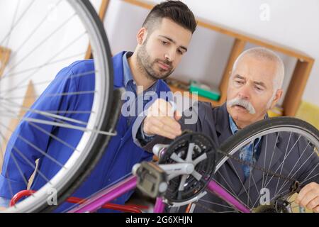 teen boy and grandfather fixing bike Stock Photo