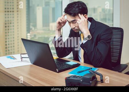 Worried young businessman having headache at workplace Stock Photo