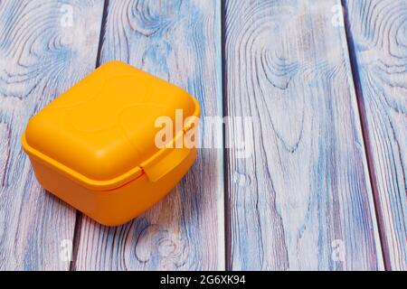 Plastic yellow lunch box on wooden background. Stock Photo