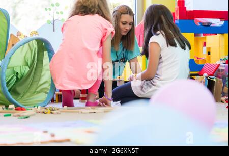 Young dedicated kindergarten teacher coordinating a fun activity for the kids during interactive playtime in the classroom Stock Photo