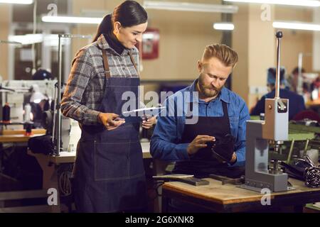 Two shoe factory workers checking the quality of new footwear at manufacturing workshop Stock Photo