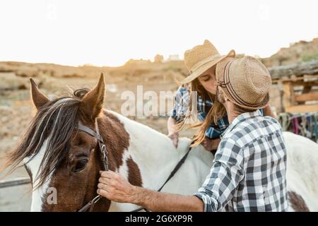 Happy couple of farmers kissing while riding on horse inside corral ranch Stock Photo
