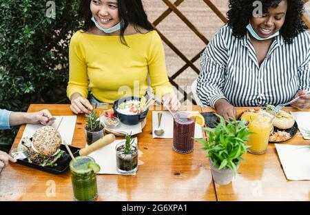 Young multiracial friends having healthy lunch in coffee brunch bar during covid19 Stock Photo
