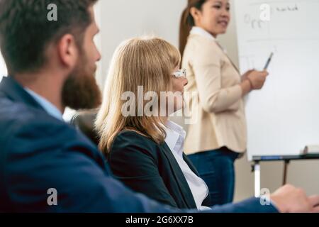 Side view of a middle-aged business woman presenting her vision and opinion about a project during a decision-making meeting in the conference room Stock Photo