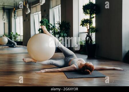 Woman doing abs exercisis with fit ball on yoga mat Stock Photo