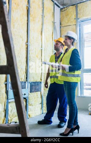 Construction manager and architect checking the insulation works in a half finished project Stock Photo