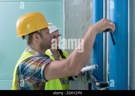 Construction workers measuring pipes on site with tape Stock Photo
