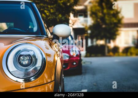 Otange and red compact cars with prominent headlights parked in single file Stock Photo