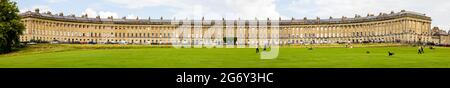 Tourists relax on the grass in front of a panoramic view of the Georgian Royal Crescent, Bath, Somerset, England. Stock Photo