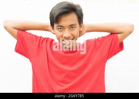 Indonesian guy with his hands on his neck looking at the camera with a disappointed face expression Stock Photo