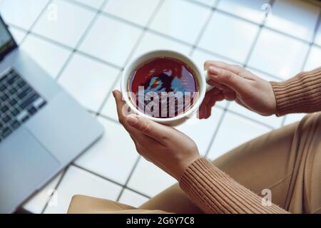 Close up of female hands holding cup with black tea Stock Photo