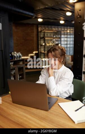Happy woman working on portable laptop at cafe Stock Photo