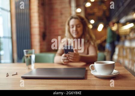 Woman sitting at cafe and using smartphone Stock Photo