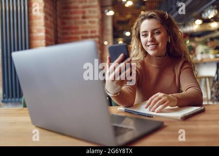 Happy woman using earphones and smartphone for video chat Stock Photo