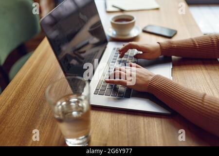 Woman working on laptop with cup of coffee on table Stock Photo