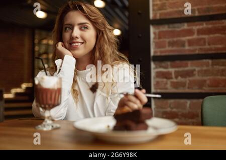 Pretty woman sitting at cafe with dessert and coffee Stock Photo