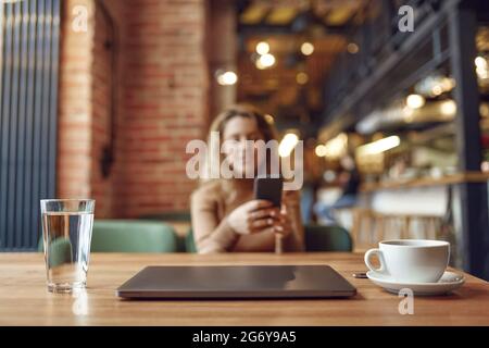 Woman using laptop and smartphone at cafe Stock Photo