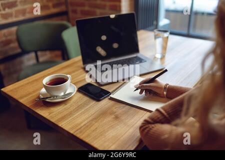 Woman taking notes while working at cafe Stock Photo
