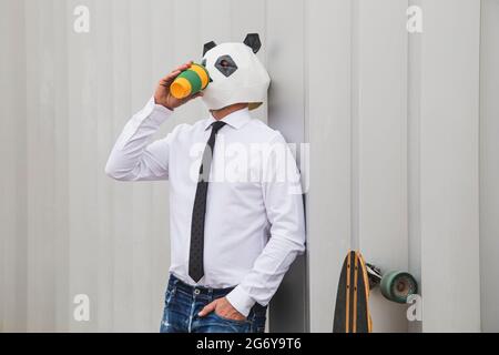 Businessman with panda bear mask drinking coffee Stock Photo
