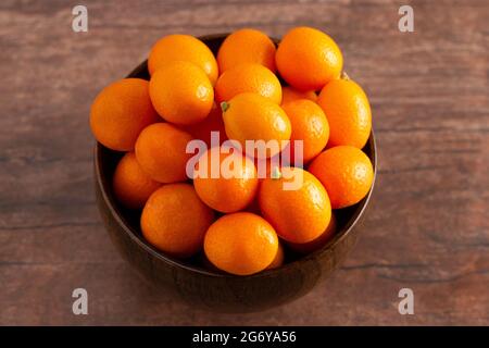 A Bowl of Fresh Kumquats on a Rustic Wooden Table Stock Photo