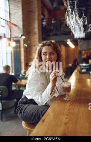 Attractive woman drinking tasty cocoa from straw at cafe Stock Photo