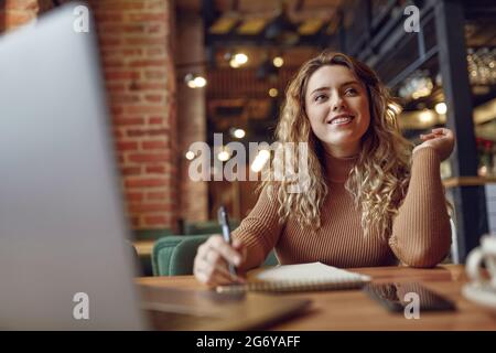 Pretty woman sitting at table with laptop Stock Photo