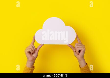 Cloud computing concept, hands holding cloud over yellow background, cloud storage Stock Photo