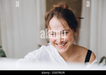 Positive woman painting on canvas in art studio Stock Photo