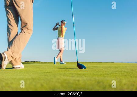 Low-angle full length view of a female professional golfer hitting a long shot, during a challenging matchplay game for two players outdoors in a sunn Stock Photo