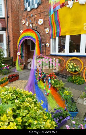 Leicester, Leicestershire, UK 9th July 2021. UK News. Mixed-media artist Alison Carpenter-Hughes with her art installation ‘Blooming Lovely,’  on the front of her house in Aylestone, Leicester. Mixing textiles and flowers to bring an element of colour and nature into the city the art work has been commission by Vehicle Arts for the ‘Up Your Street’ project. As there has been such a lack of access to the arts over this last year, the premise of the project is to brighten up the streets in the local area and to get people engaged. Credit: Alex Hannam/Alamy Live News Stock Photo