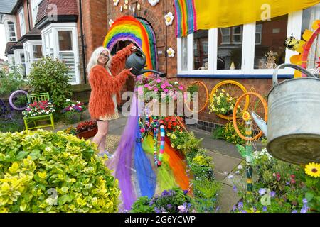 Leicester, Leicestershire, UK 9th July 2021. UK News. Mixed-media artist Alison Carpenter-Hughes with her art installation ‘Blooming Lovely,’  on the front of her house in Aylestone, Leicester. Mixing textiles and flowers to bring an element of colour and nature into the city the art work has been commission by Vehicle Arts for the ‘Up Your Street’ project. As there has been such a lack of access to the arts over this last year, the premise of the project is to brighten up the streets in the local area and to get people engaged. Credit: Alex Hannam/Alamy Live News Stock Photo