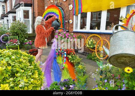 Leicester, Leicestershire, UK 9th July 2021. UK News. Mixed-media artist Alison Carpenter-Hughes with her art installation ‘Blooming Lovely,’  on the front of her house in Aylestone, Leicester. Mixing textiles and flowers to bring an element of colour and nature into the city the art work has been commission by Vehicle Arts for the ‘Up Your Street’ project. As there has been such a lack of access to the arts over this last year, the premise of the project is to brighten up the streets in the local area and to get people engaged. Credit: Alex Hannam/Alamy Live News Stock Photo