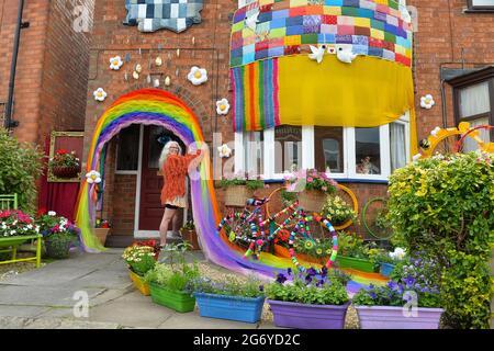 Leicester, Leicestershire, UK 9th July 2021. UK News. Mixed-media artist Alison Carpenter-Hughes with her art installation ‘Blooming Lovely,’  on the front of her house in Aylestone, Leicester. Mixing textiles and flowers to bring an element of colour and nature into the city the art work has been commission by Vehicle Arts for the ‘Up Your Street’ project. As there has been such a lack of access to the arts over this last year, the premise of the project is to brighten up the streets in the local area and to get people engaged. Credit: Alex Hannam/Alamy Live News Stock Photo