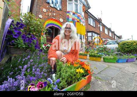 Leicester, Leicestershire, UK 9th July 2021. UK News. Mixed-media artist Alison Carpenter-Hughes with her art installation ‘Blooming Lovely,’  on the front of her house in Aylestone, Leicester. Mixing textiles and flowers to bring an element of colour and nature into the city the art work has been commission by Vehicle Arts for the ‘Up Your Street’ project. As there has been such a lack of access to the arts over this last year, the premise of the project is to brighten up the streets in the local area and to get people engaged. Credit: Alex Hannam/Alamy Live News Stock Photo