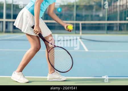 Side view low section of a young woman wearing white skirt and tennis shoes while serving during professional match Stock Photo