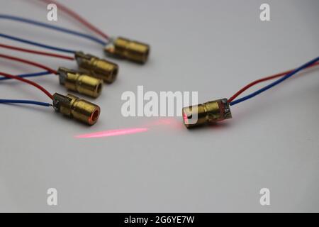 Laser diode which is small and has copper casing in group with one diode emitting red laser light Stock Photo