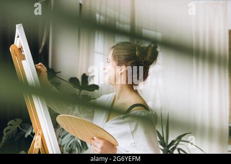 Side view of woman using brush and color palette for art Stock Photo
