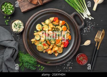 Fried vegetables, fresh herbs and sauces on a black background. Top view. Stock Photo