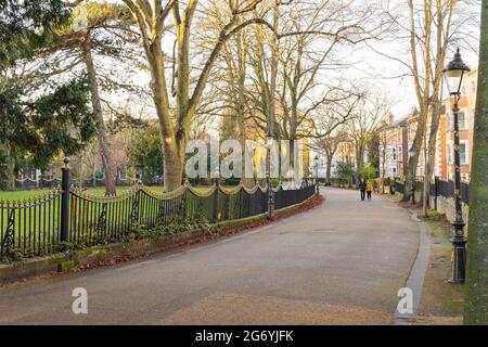 New Walk near University Road and The Oval, shows 2 people walking down the curving to the left walkway. Tree-lined walkway with railings on the left. Stock Photo