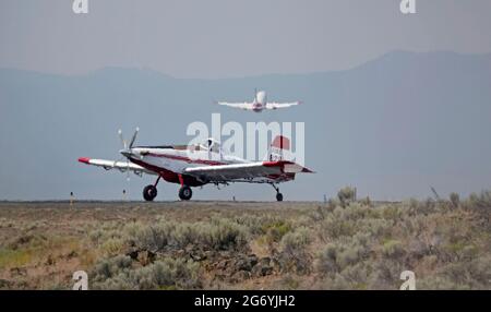 An Air Tractor carrying the fire boss, and a Coulson Flying Tanker 737 loaded with fire retardent, take off in 114 degree heat from the Redmond, Orego Stock Photo