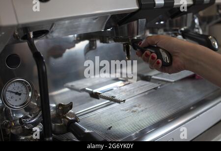 Female's hand operating the  Automatic Coffee  machine to make coffee Stock Photo