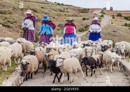 AMANTANI, PERU - MAY 15, 2015: Native women with their sheep on Amantani island in Titicaca lake, Peru Stock Photo