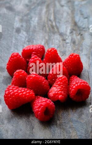 Closeup photograph of delicious raspberries on grey slate background Stock Photo