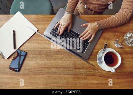 Close up of female freelancer using laptop at cafe Stock Photo