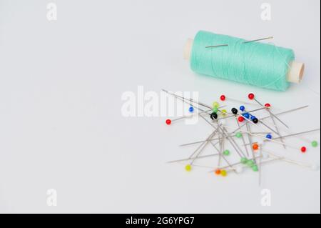 sewing thread and pins on white background with copy space Stock Photo