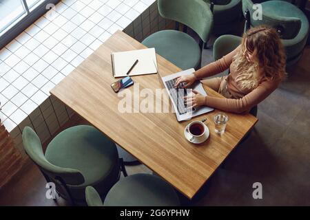 Busy woman sitting at table and using laptop Stock Photo