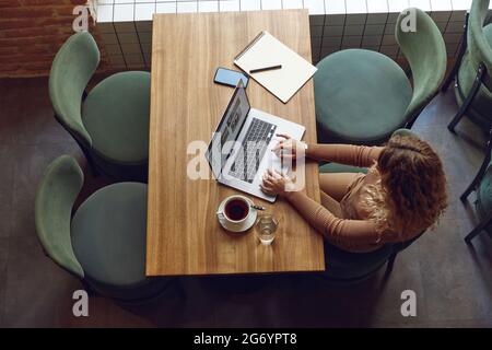 Woman working on laptop at cafe Stock Photo